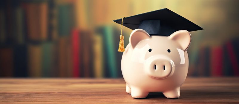 Scholarship with piggy bank and graduation cap on table text space