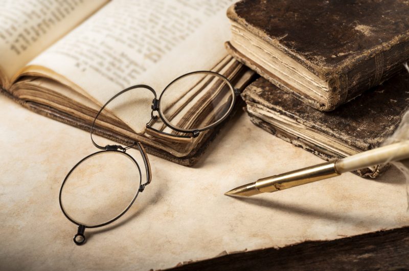 antique books and spectacles on old parchment